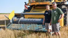 Jean-Yves Louedec, à droite, et Erwan Le Merrer, de l'ETA de Saint- Nicodème qui réalise la moisson, devant la moissonneuse équipée du bec pick-up à courroie.