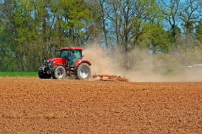 Tracteur qui travaille dans un champ sec et poussiéreux.