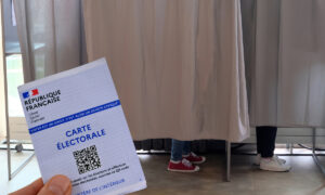 Carte électorale tenue en main devant des isoloirs