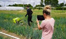 Une femme et un homme dans un champ en train de mesurer des points de tension grâce à une combinaison connectée