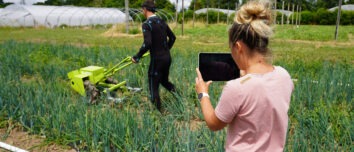 Une femme et un homme dans un champ en train de mesurer des points de tension grâce à une combinaison connectée