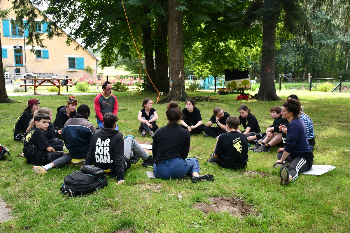 Les jeunes et les éducateurs assis en rond au milieu des arbres