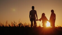 Une famille qui se tient la main devant un coucher de soleil