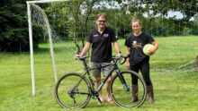 Un éleveur avec son vélo accompagné par sa salariée tenant un ballon de football.