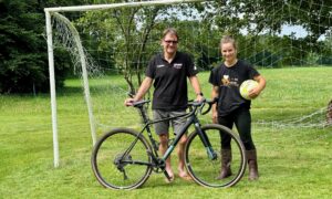 Un éleveur avec son vélo accompagné par sa salariée tenant un ballon de football.