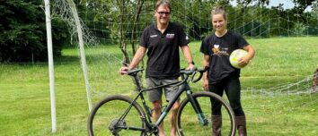 Un éleveur avec son vélo accompagné par sa salariée tenant un ballon de football.