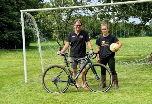 Un éleveur avec son vélo accompagné par sa salariée tenant un ballon de football.