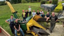 Des agriculteurs et leurs enfants autour d'une ensileuse ancienne deux rangs.