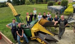 Des agriculteurs et leurs enfants autour d'une ensileuse ancienne deux rangs.