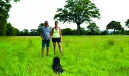 Les éleveurs dans une parcelle avec leur chien et un arbre dans le fond