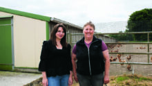 Deux femmes devant un bâtiment de poules pondeuses.