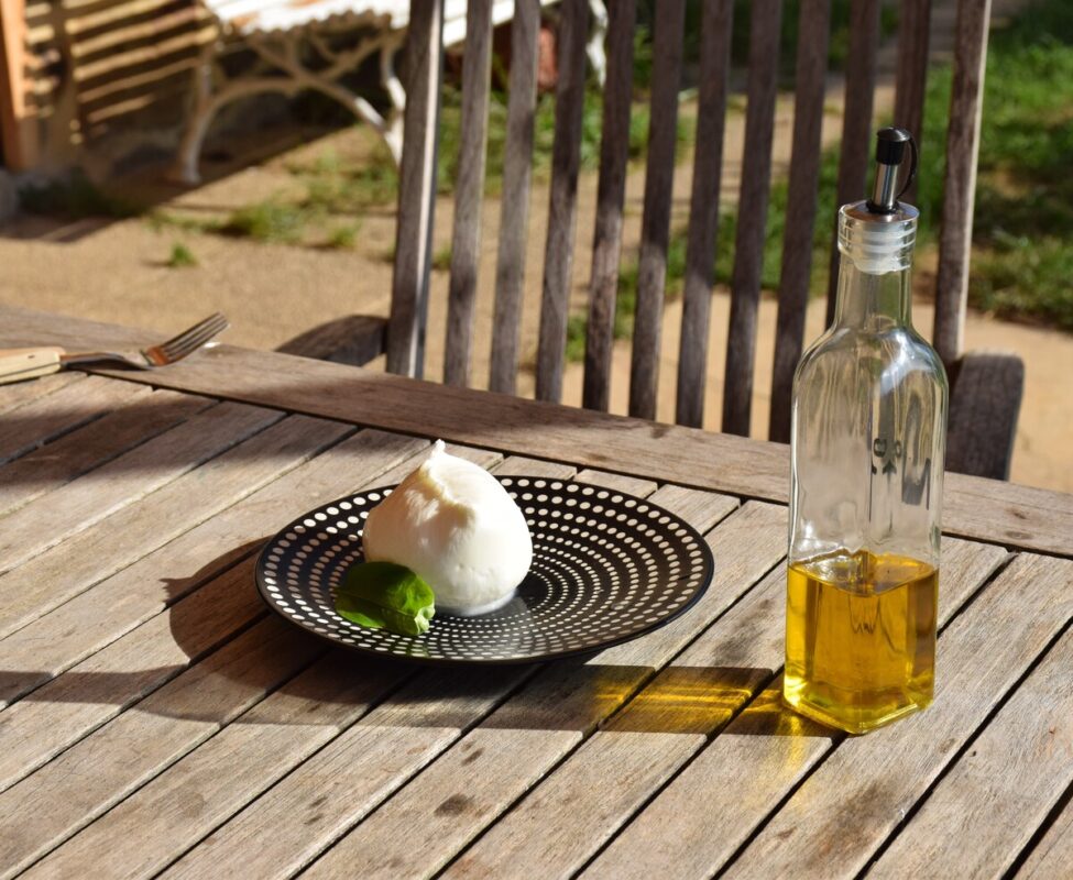 Une boule de mozzarella agrémentée d'une feuille de basilic et arrosée d'un filet d'huile d'olive.