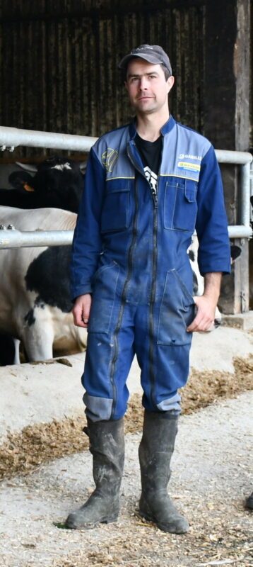 Erwan Toulgoat devant ses bovins avec son bleu de travail