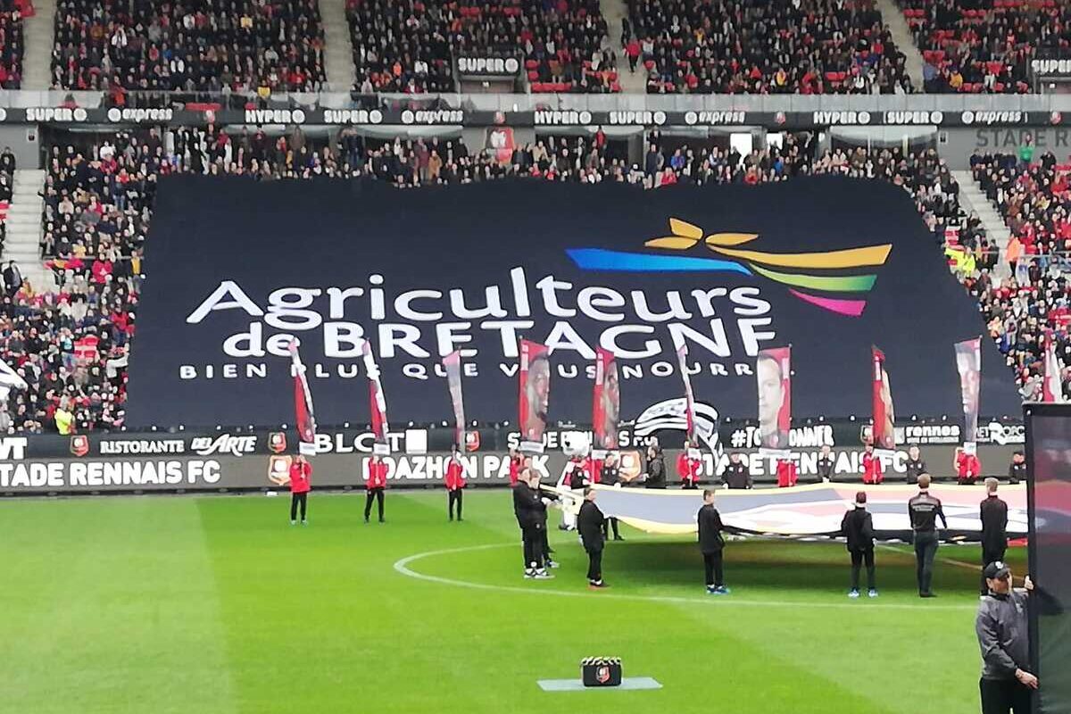 Le drapeau Agriculteurs de Bretagne déployé dans une tribune d'un stade de foot - Illustration La Ferme au Moustoir