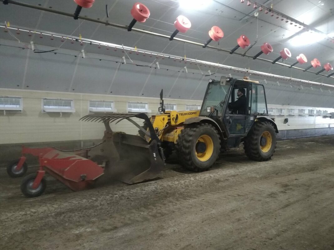 L'éleveur passe la balayeuse attachée à son godet