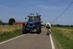 un tracteur et des vélos se croisent sur une route de campagne