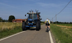 un tracteur et des vélos se croisent sur une route de campagne