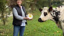 Estelle Viel dans un champ avec un fromage au lait cru et une vache