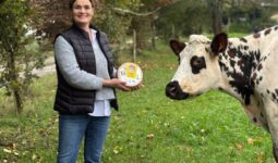 Estelle Viel dans un champ avec un fromage au lait cru et une vache