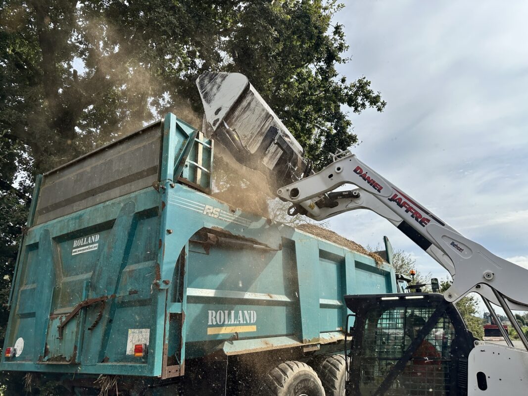 bobcat en train de vider son godet dans une remorque