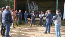 Groupe de personnes devant un hangar agricole