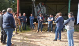 Groupe de personnes devant un hangar agricole