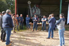 Groupe de personnes devant un hangar agricole