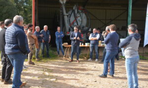 Groupe de personnes devant un hangar agricole