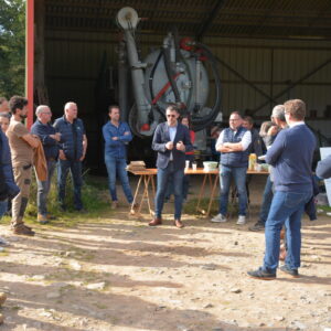 Groupe de personnes devant un hangar agricole