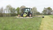 Un tracteur réalise un chantier de fauche de l'herbe.