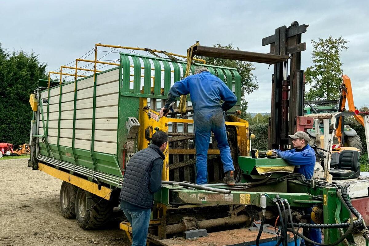 Deux mécaniciens agricoles et un éleveur autour d'une remorque en réparation - Illustration Cuma : L’activité dépendante de la main-d’œuvre