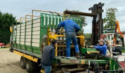 Deux mécaniciens agricoles et un éleveur autour d'une remorque en réparation