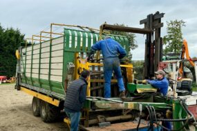 Deux mécaniciens agricoles et un éleveur autour d'une remorque en réparation