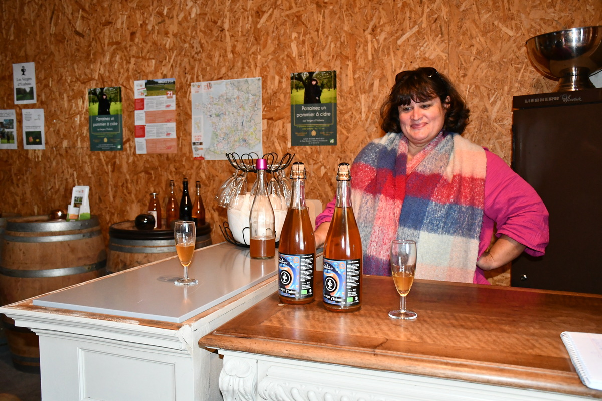 La productrice derrière un comptoir avec ses bouteilles de cidre dessus