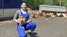 Une jeune femme souriante avec un poulet dans les mains