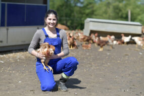 Une jeune femme souriante avec un poulet dans les mains