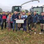 Un groupe de jeunes agriculteurs devant une ensileuse et un tracteur