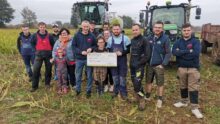 Un groupe de jeunes agriculteurs devant une ensileuse et un tracteur