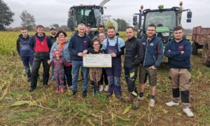 Un groupe de jeunes agriculteurs devant une ensileuse et un tracteur