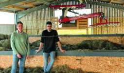 Un couple d'éleveur dans  leur installation de séchage en grange remplie de foin et équipée d'une griffe de reprise.