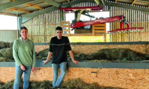 Un couple d'éleveur dans  leur installation de séchage en grange remplie de foin et équipée d'une griffe de reprise.