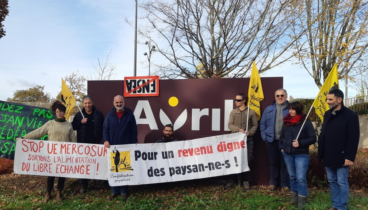 Les manifestants devant le panneau du groupe Avril - Illustration « Rompre avec  le libre-échange »