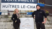 Un couple devant la banderole de vente directe des huîtres Le-Cha