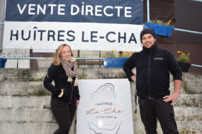 Un couple devant la banderole de vente directe des huîtres Le-Cha