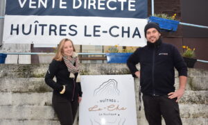 Un couple devant la banderole de vente directe des huîtres Le-Cha