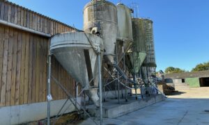 Des silos d'aliments à côté d'un bâtiment d'élevage laitier