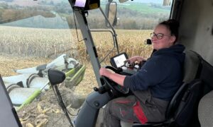 Une jeune femme au volant dans une cabine de moissonneuse