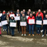 Les membres de la liste portent des panneaux et drapeaux devant une stabulation