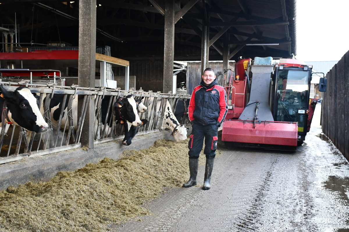 Alexis Robert devant la mélangeuse dans le couloir d'alimentation avec les vaches - Illustration L’automotrice rationalise la distribution