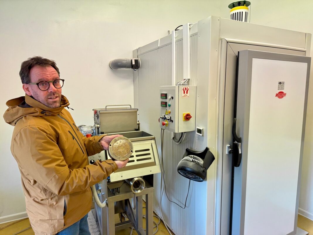 Un paysan pastier dans son laboratoire de fabrication devant une machine et un séchoir